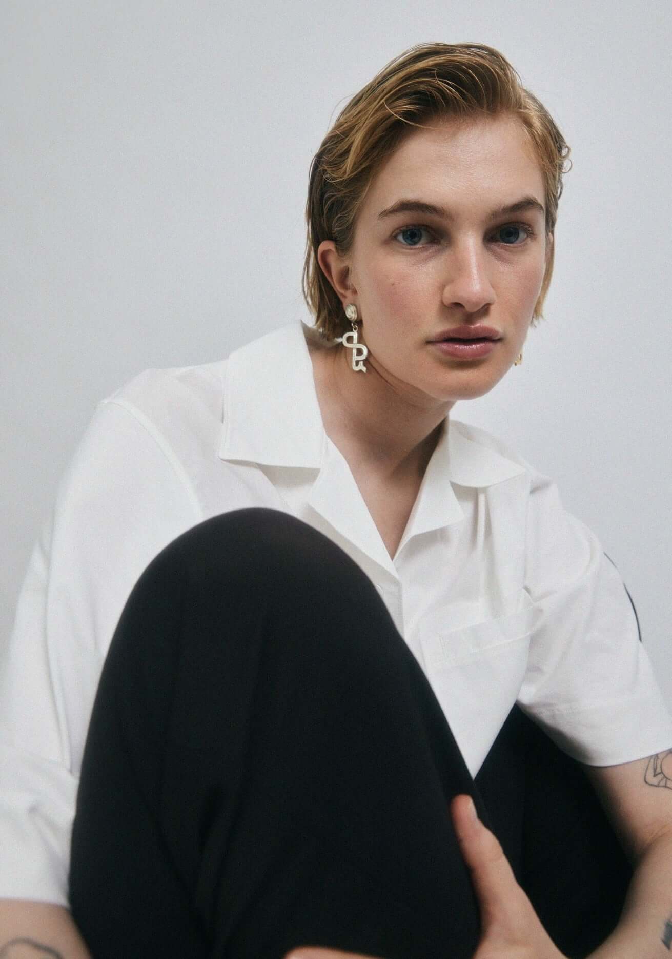 Model sitting, wearing silver earrings